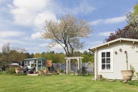 English garden in rural East Anglia in Norfolk. Large outside private garden with trees potting shed and summerhouse. Grass lawn and flower beds in spring time.の写真素材