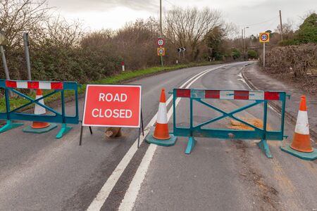 Road closed with barrier and signage. Rural highway shut with signs and safety fences.の写真素材