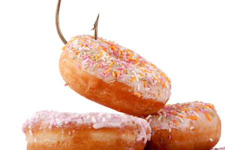 Donut cake caught with a hook. Addicated to food and sugar concept on a white background. Bad diet conceptの写真素材