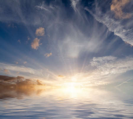 Dawn sunrise landscape out at sea with no land or people. Ocean reflection with amazing clouds and skyの写真素材