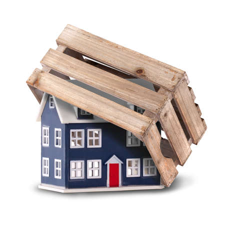 Home protection and security concept with a small house protected with a big strong crate.Isolated on a white backgroundの写真素材
