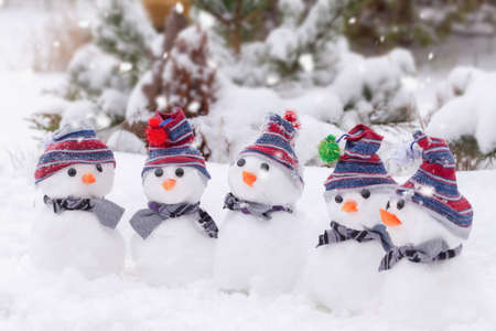 Cute little snowmen with hats and scarfs grouped in a winter wonderland of snow.の写真素材