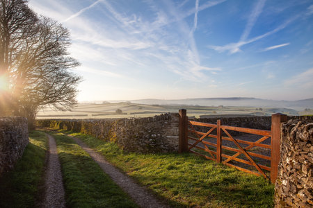 Sunrise in the Peak District. Wooden farm  gate and dry stone walls with frosty fields and blue skiesの写真素材