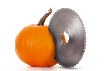 Pumpkin carving concept with a large spinning circular saw blade cutting the pumkin on a white isolated studio backgroundの写真素材