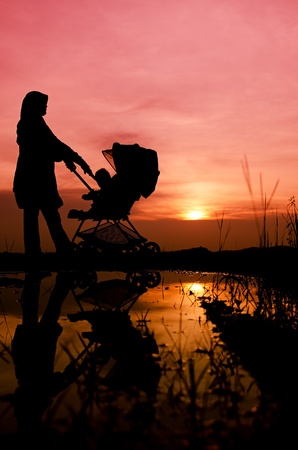 Muslim mother and baby walking during sunset with stroller の写真素材