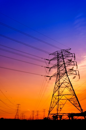 Silhouette electricity pylons during sunsetの写真素材