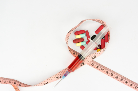 pills, syringe and measuring tape with shallow depth of field (dof) - risk diet and healthy conceptの写真素材