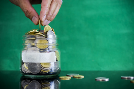 Hand putting coin into jar. Copy space concept for saving fund, financial, banking, investment,...