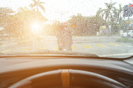 Driving in rain at sunset. Road view through car window with rain drops.の写真素材