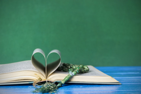 Close up hardcover book with tasbih or breads isolated on green background. Holy spirituality book concept. Selective focus.の写真素材