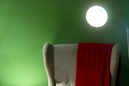 Comfortable armchair in cosy setting with wall lights are lit at night.の写真素材