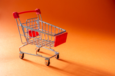 Close up shopping trolley on orange background with copy spaceの写真素材
