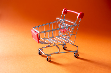Close up shopping trolley on orange background with copy spaceの写真素材