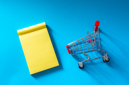 Trolley and notes isolated on blue background. Copy space and top view.の写真素材