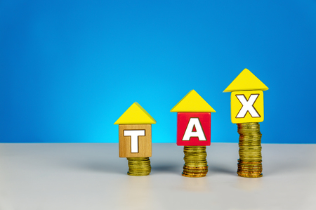 Property TAX. Build a house from wood cubes with stacking coin. Tax and taxation concept or other your content.の写真素材