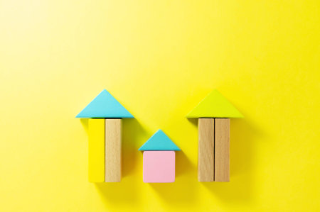 House toy wood blocks on yellow background. Little wooden house. Hard light and long shadows effect.の写真素材