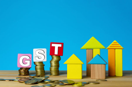 GST for properties. Building from wood cubes stacking with gold coin. Tax, taxation, property and investment concept or other your content.の写真素材