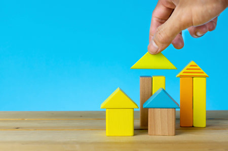 Investment for real estate. Playing with wooden cubes. Hand holding wooden house. Investment, saving and development concept or other your content.の写真素材