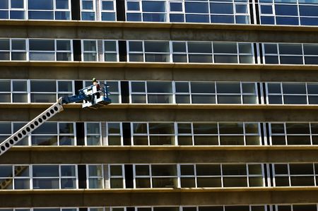 Maintenance worker in a crane inspecting a new residential building