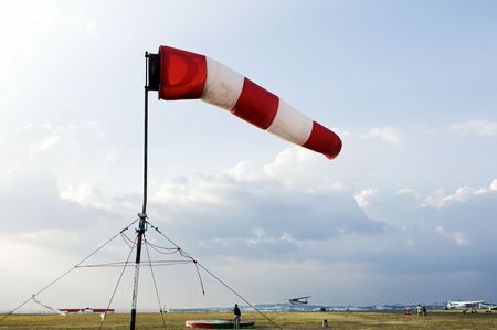 A red and white windsock flying in the wind to signal direction on an airfieldの写真素材