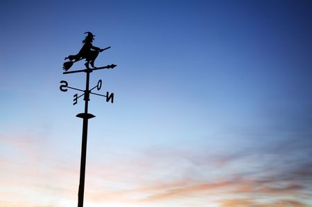A silhouette of a weather vane with a witch on top. の写真素材