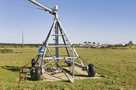 Irrigation pivot axis in a green plane near a small villageの写真素材
