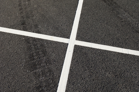 Detail of tire marks and white stripes painted on the roadの写真素材
