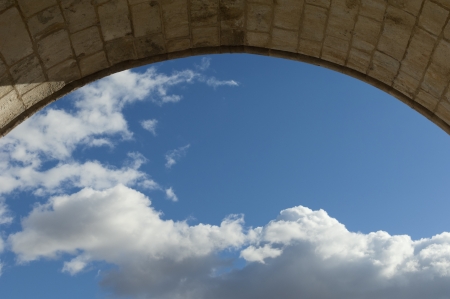 View of the sky with clouds through an old stone archwayの写真素材