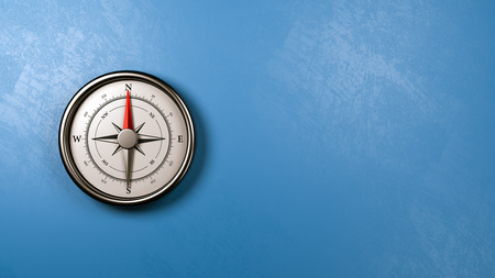 Metallic Compass with Red Magnetic Needle Pointing Toward the North Against a Plastered Blue Wall with Copyspace, 3D Illustrationの写真素材