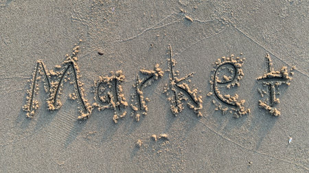 Market written gracefully in the sand at the beach for business advertising or financial planning conceptsの素材