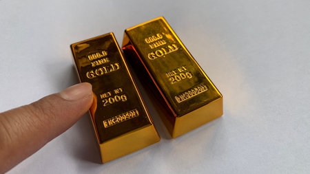 Two gold bars placed side by side with finger pointing, highlighting engraved â€œfine goldâ€ text and comparable size