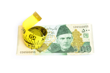 Closeup of five hundred rupee Pakistani currency bill with measure tape for budget cut conceptsの写真素材