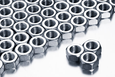 Metallic nuts arranged in rows on a white background