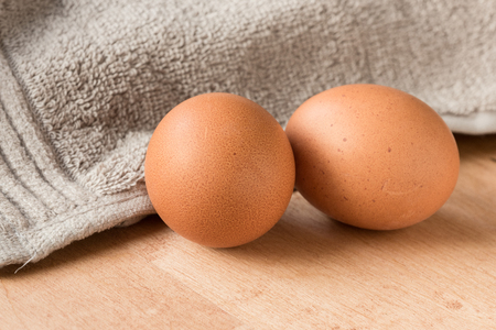 Two brown eggs on a wooden kitchen table.の写真素材