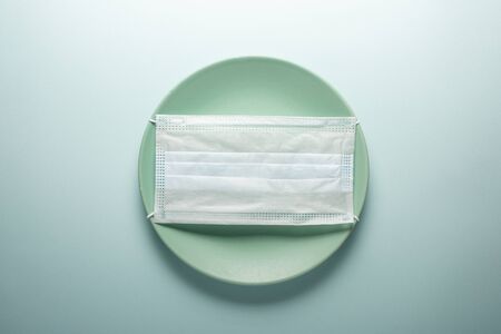 Disposable medical mask on a round plate. Concept photo.