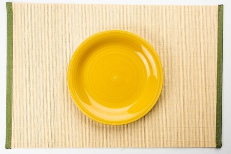 Yellow plate on a bamboo napkin, top viewの写真素材