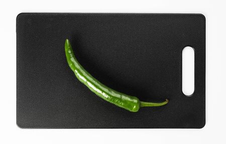 Green hot pepper on a black cutting boardの写真素材