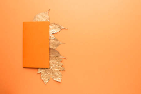 Blank card with gold leaves on orange. Autumn concept.