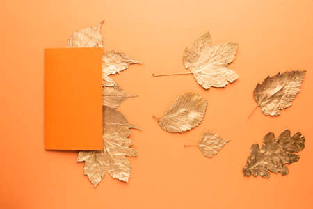 Blank card with gold leaves on orange. Autumn concept.