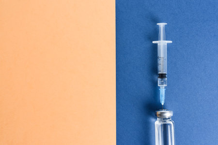Ampoules with a vaccine and a syringe on a blue background.