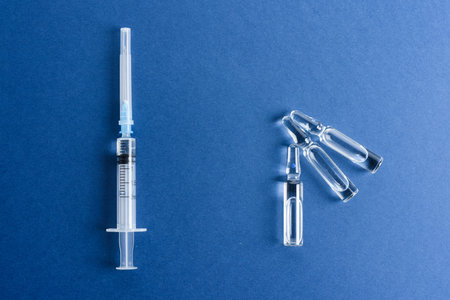 Ampoules with a vaccine and a syringe on a blue background.