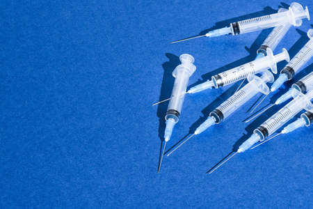 Group of disposable medical syringes for injections on blue.