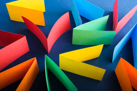 Multicolored cut paper on blue. Abstract arrows, direction signs.