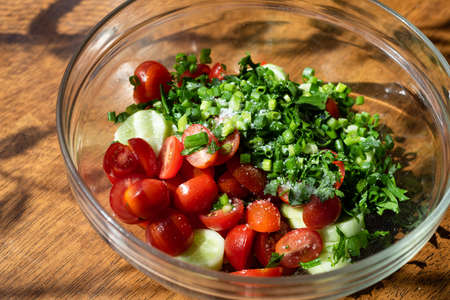 vegetable salad in a glass bowl on a wooden tableの写真素材