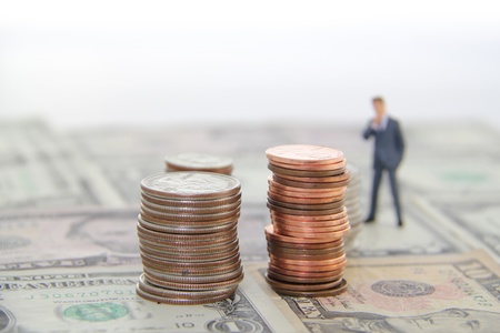 Blurred man standing on a floor made of money, looking at stacks of coins の写真素材