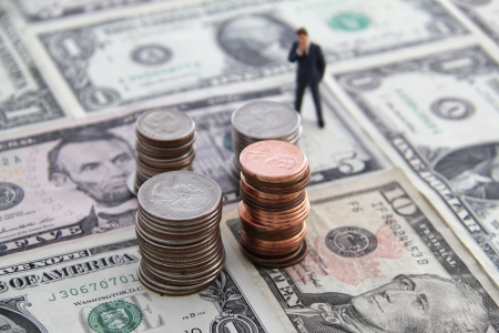 Business man staring at stacks of coins while standing on a floor made of money の写真素材