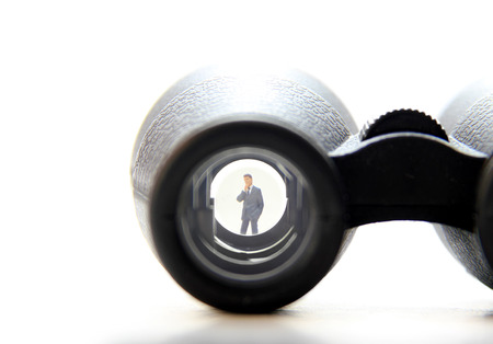 Business man figurine in the lens of binocularsの写真素材