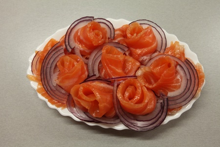 Slices of salmon with red onion on a plateの写真素材