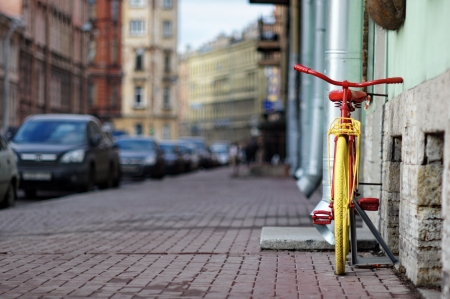 old yellow bicycle stands at the walls the city housesの写真素材