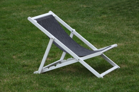 White wooden deck chair on green grassの写真素材
